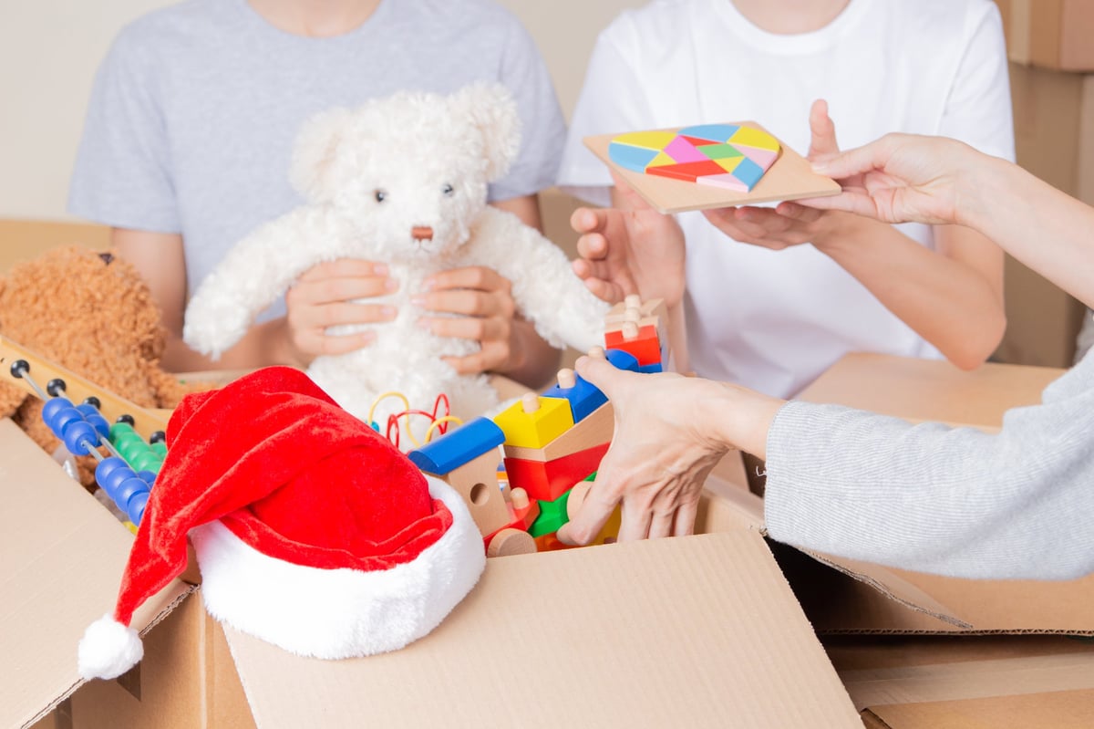 Christmas donation. Volunteers collect donations for charity indoors. Cardboard boxes with kid toys, school supplies, clothes.