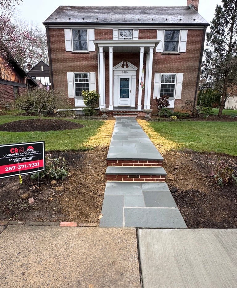 Concrete patio foundation next to residential house with wooden deck and garage door
